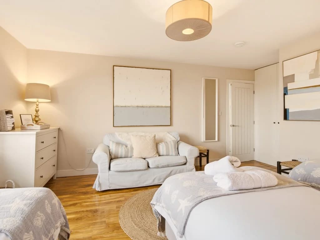 Spacious family bedroom with sofa, chest of drawers and soft neutral décor