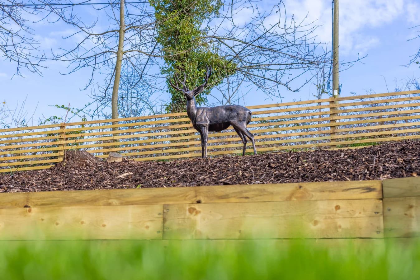 Garden feature with decorative stag sculpture and timber fencing