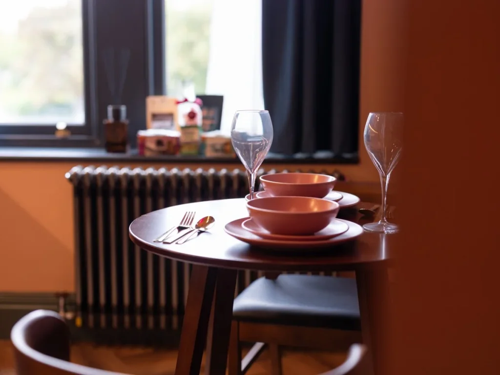 Dining table set for two beside the large window with natural light
