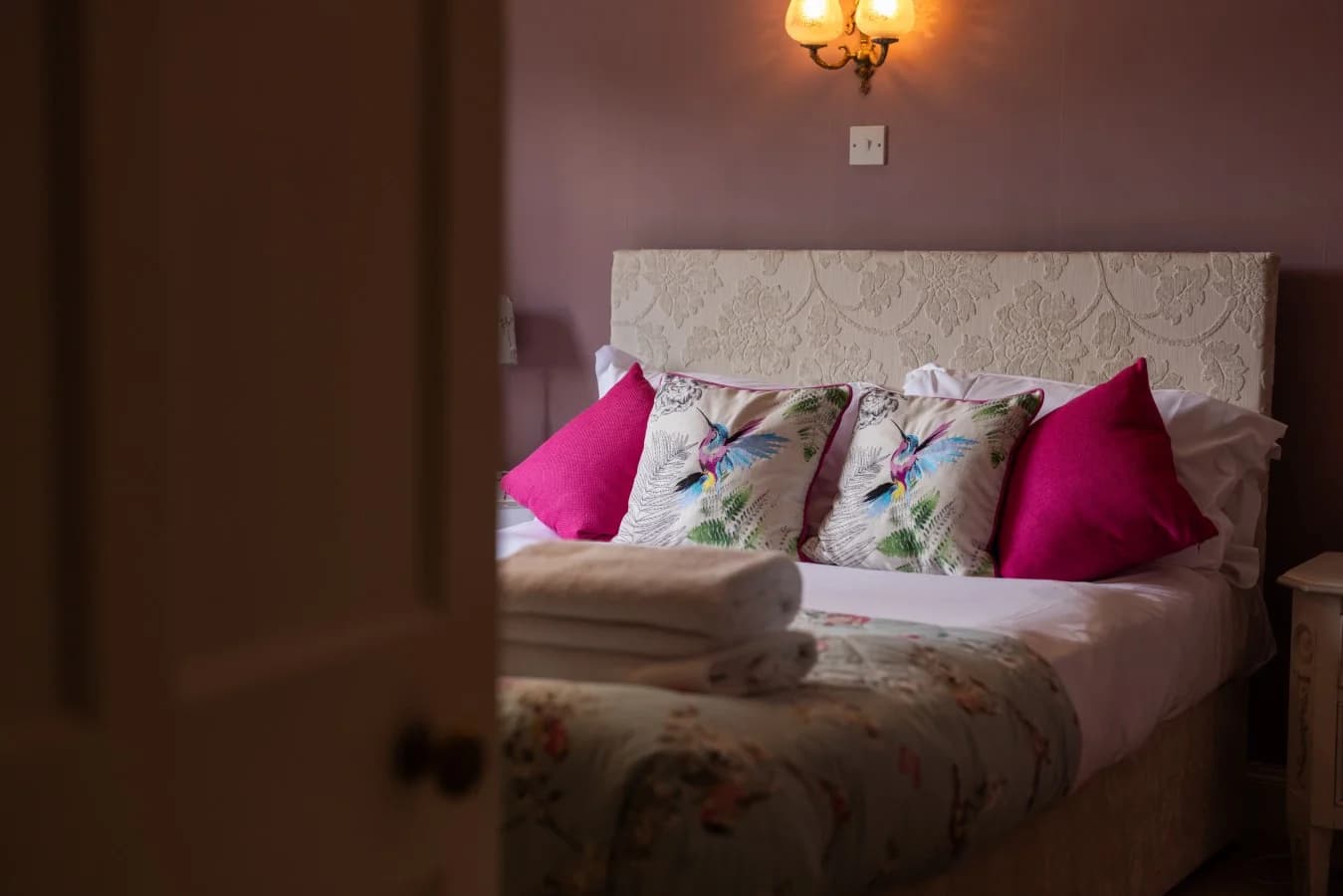 Double bedroom with upholstered headboard and floral bedding.