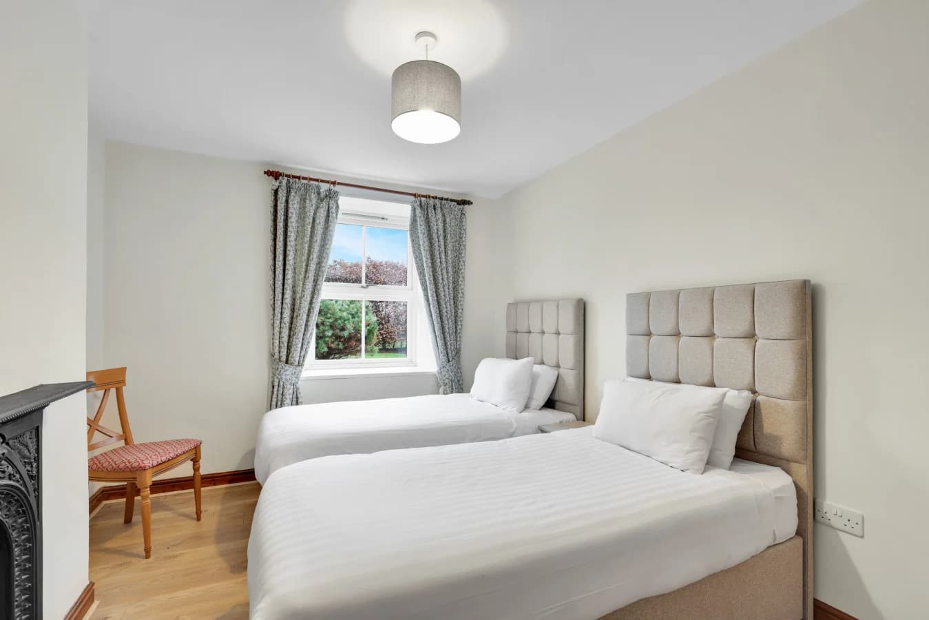Soft neutral palette and upholstered headboards create a restful feel