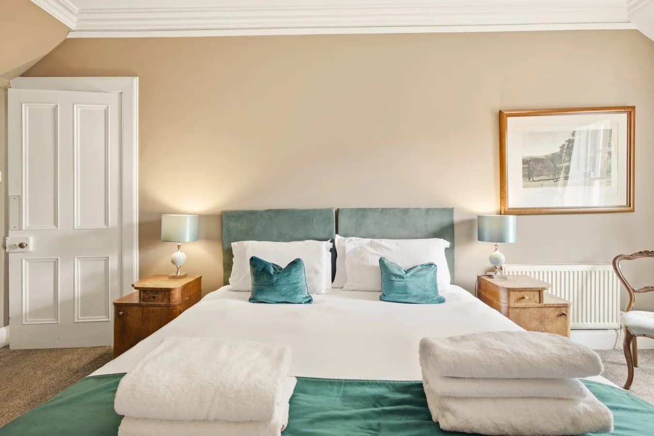 Spacious bedroom with upholstered bed, bedside tables and artwork