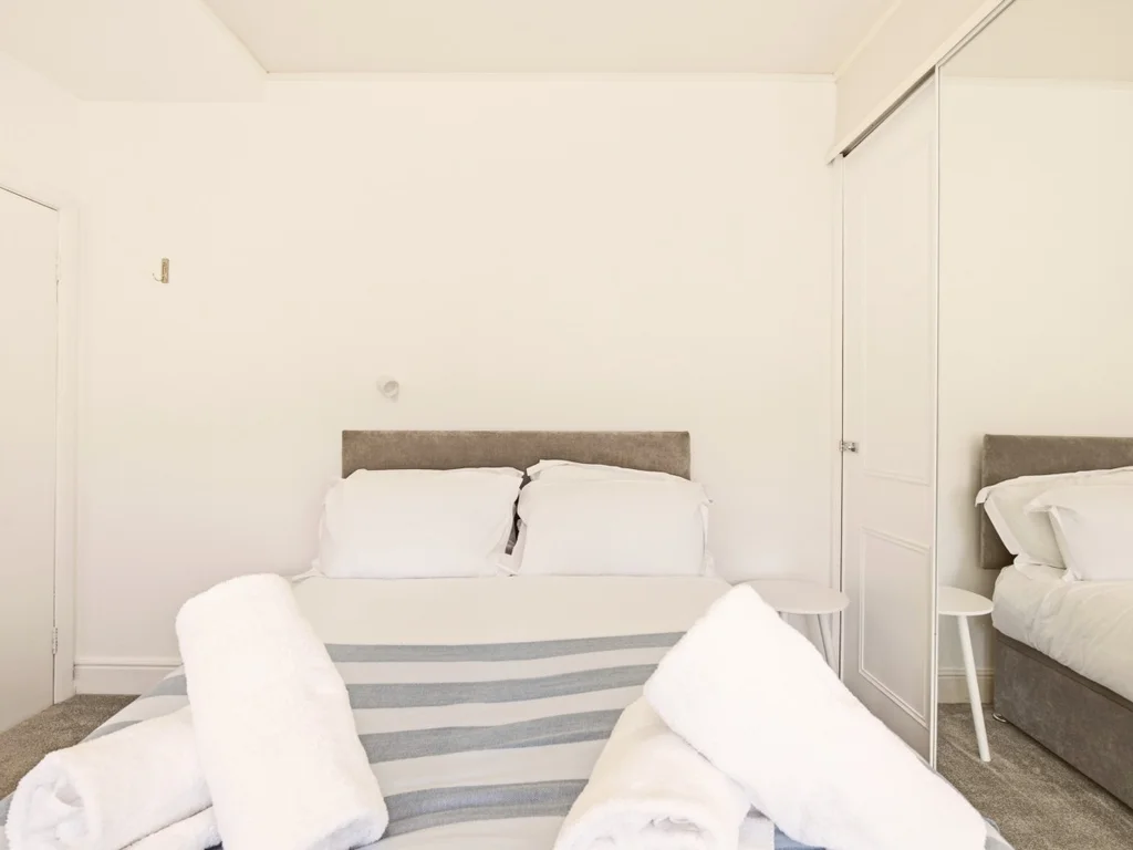 Double bedroom with fitted mirrored wardrobes and bedside table.