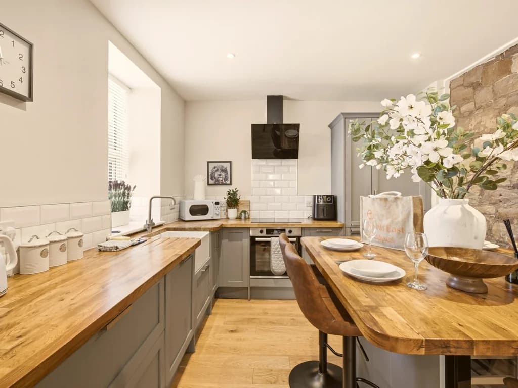 Contemporary kitchen with Belfast sink and wooden breakfast bar.