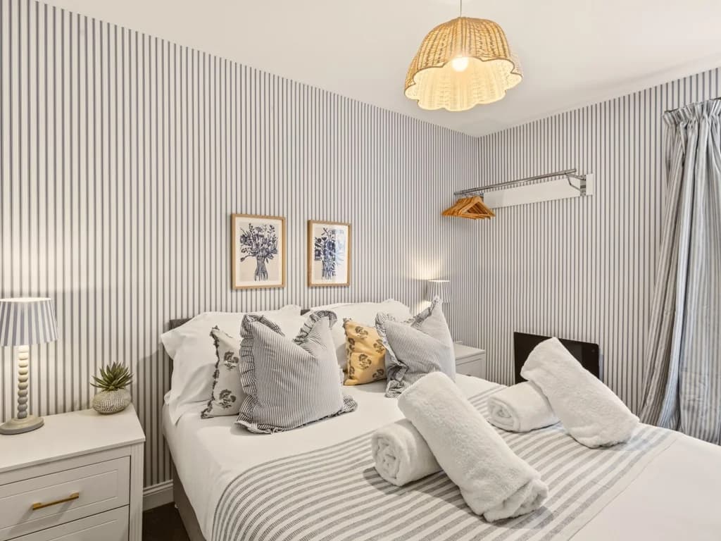 Double bedroom with striped wallpaper and coordinating soft furnishings.
