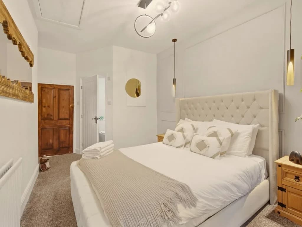 Second-floor king bedroom with tufted headboard and soft pendant lighting.