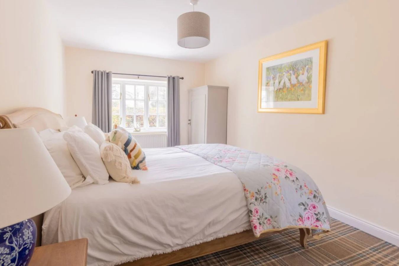 Spacious bedroom with plaid carpet, timber furnishings and artwork