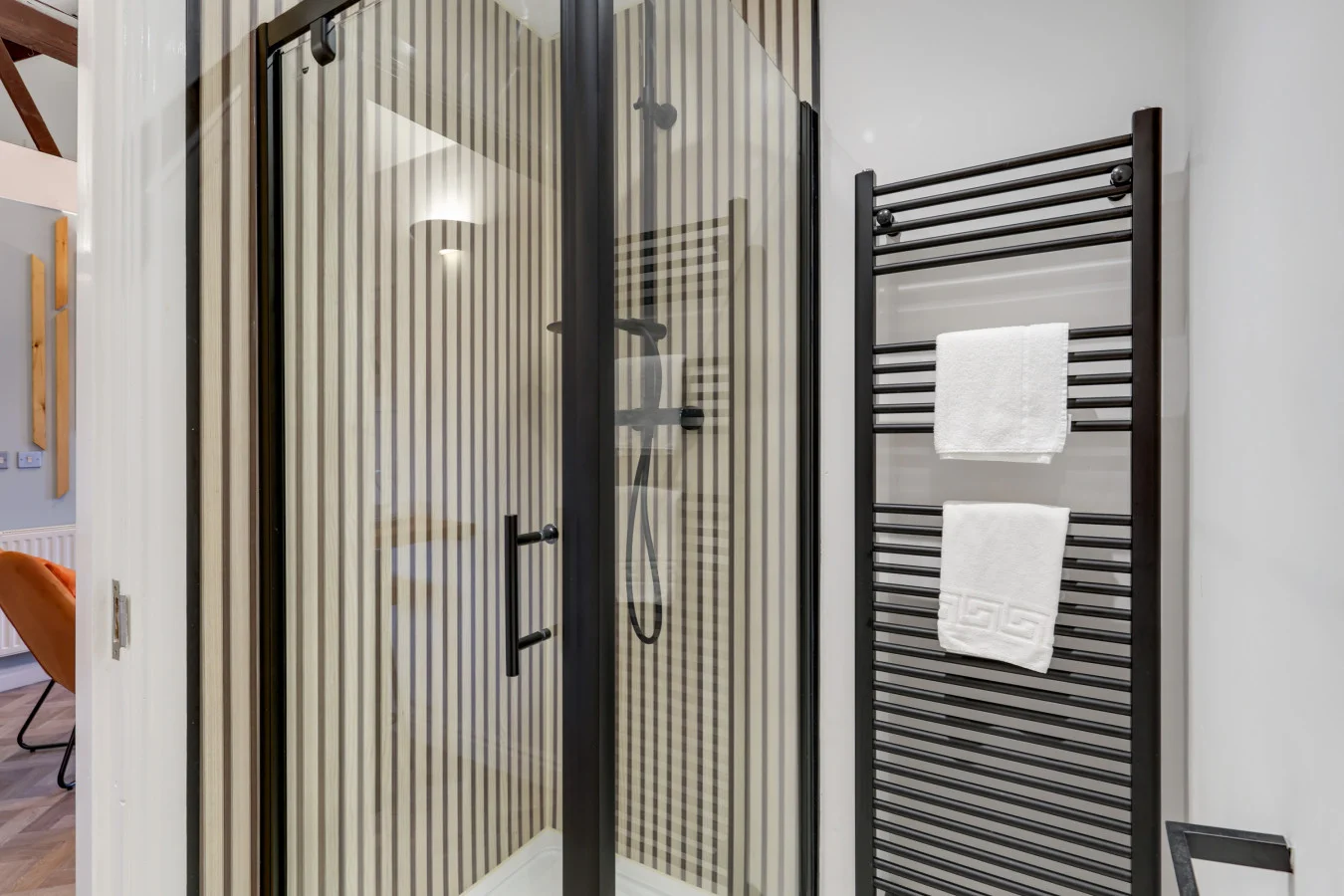 Modern shower enclosure with black-framed glass and heated towel rail