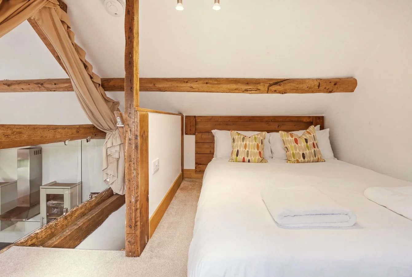 Hayloft bedroom with queen-size bed beneath exposed timber beams