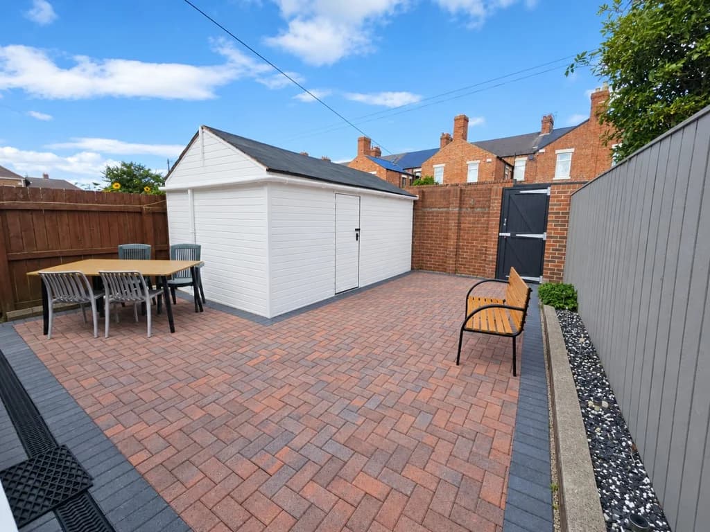 Enclosed rear patio with outdoor dining table, seating and storage shed