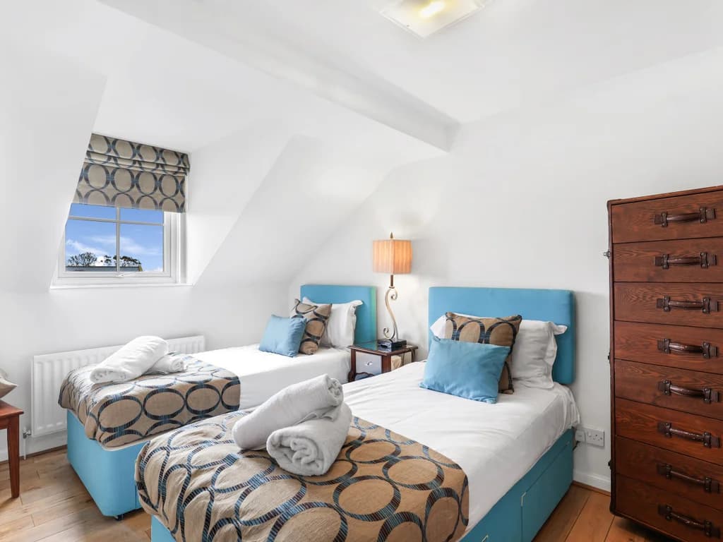 Twin bedroom with blue upholstered beds and exposed rooflines
