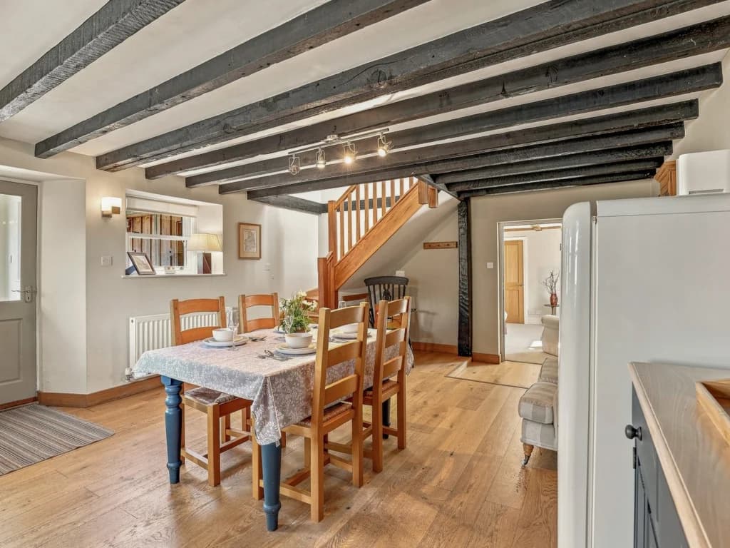 Dining area with wooden table, staircase and exposed ceiling beams