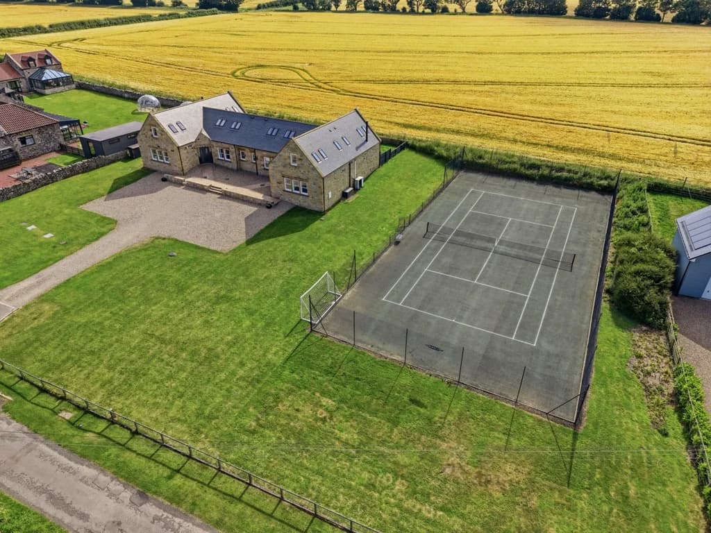 Aerial view of shared tennis court and cottage complex