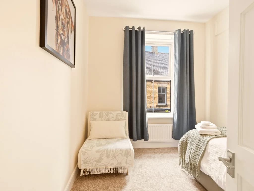 Single bedroom with upholstered day bed and soft neutral décor.