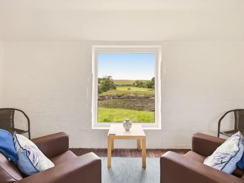 Jetty Cottage seating positioned beside a window overlooking the bay