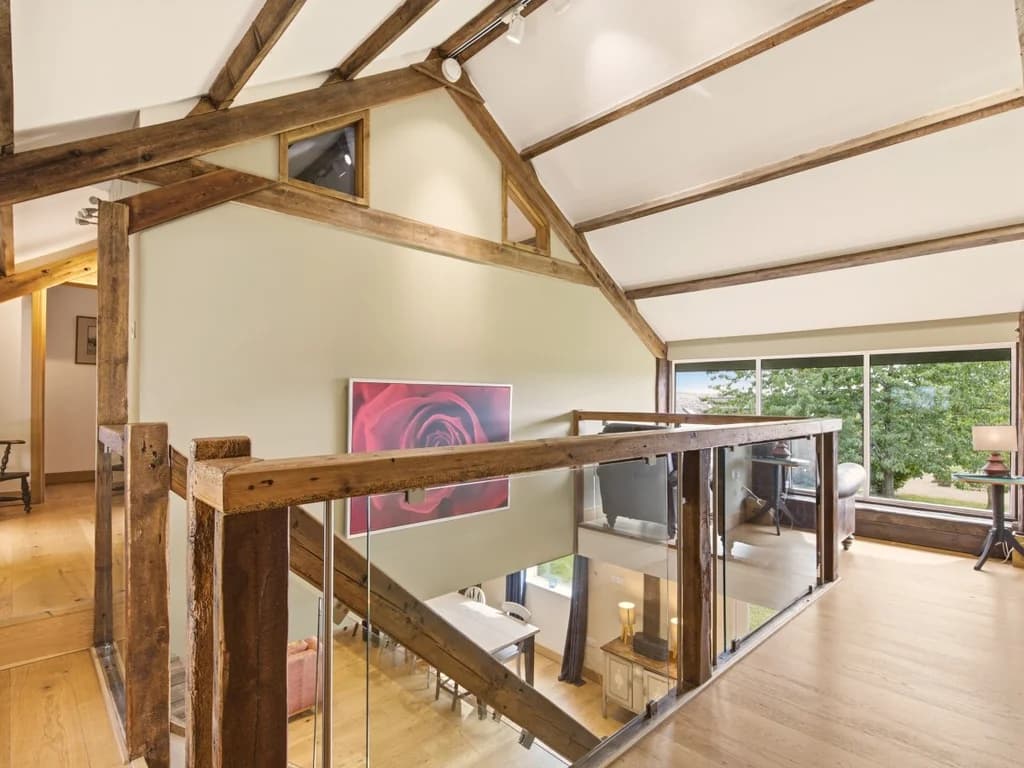 Upper landing with exposed timber beams overlooking the living area
