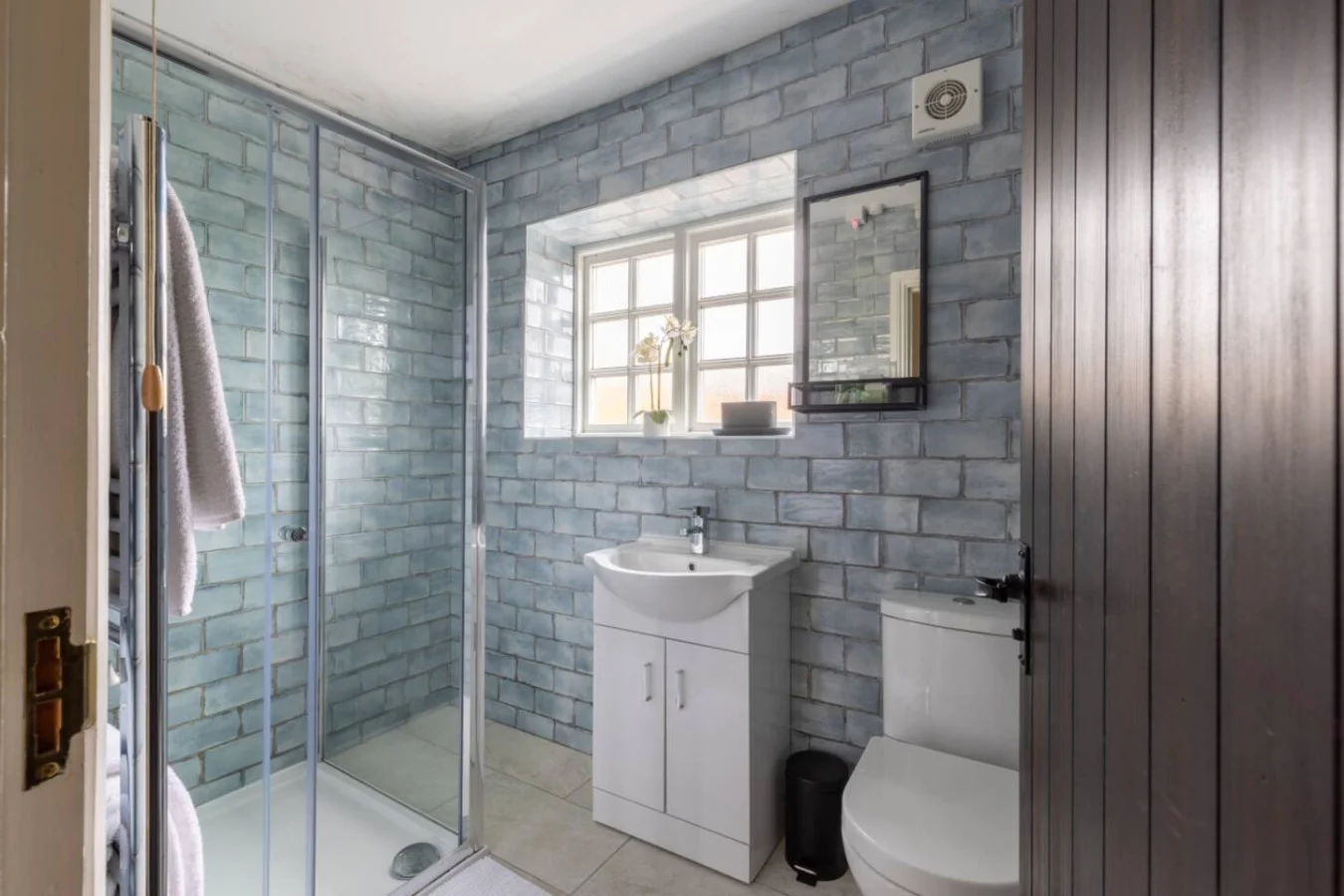 Characterful shower room with blue brick-effect tiling and natural light