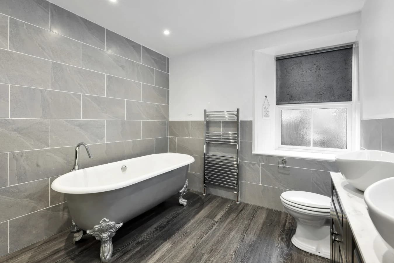 Stylish bathroom finished with grey stone tiles and classic fittings
