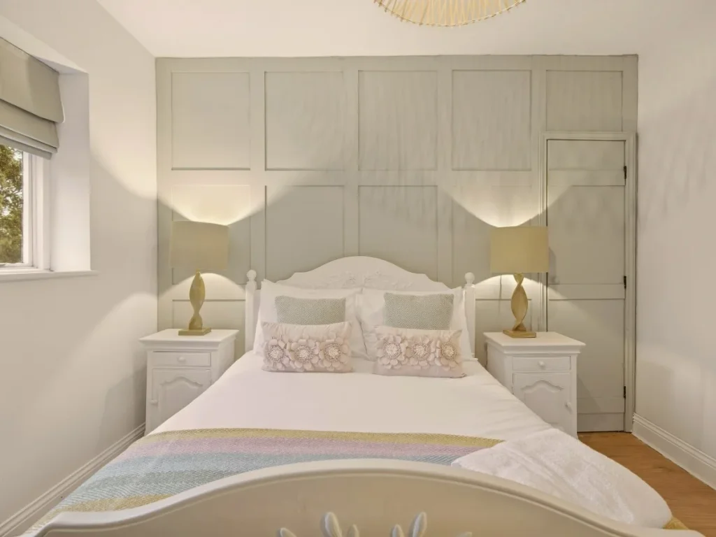 Double bedroom with panelled feature wall and matching bedside tables.
