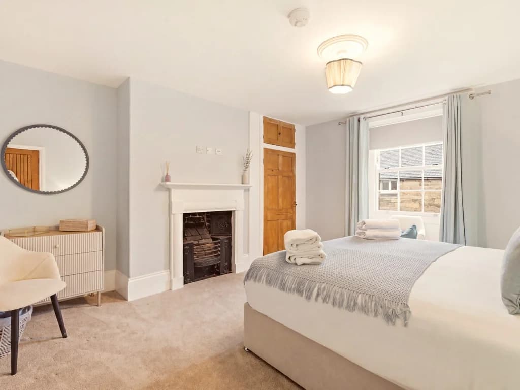Spacious King Zip bedroom with feature fireplace, dressing area and village views.