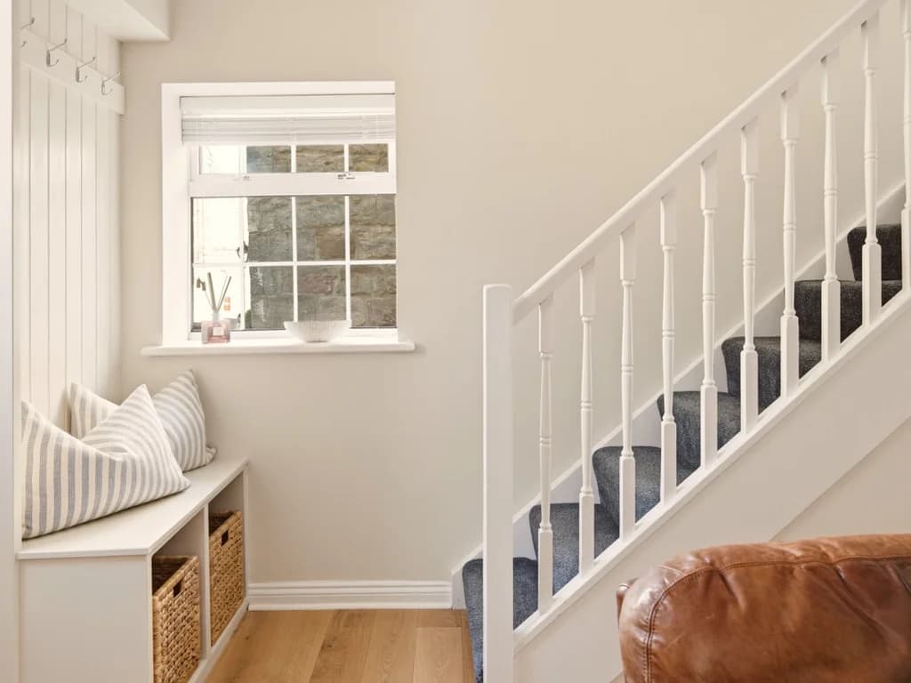 Entrance hallway with staircase, window seat and built-in storage.