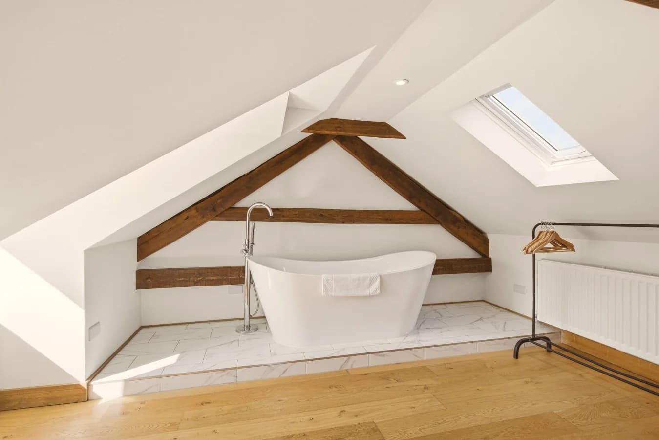 Freestanding bath beneath skylight and original exposed timber beams