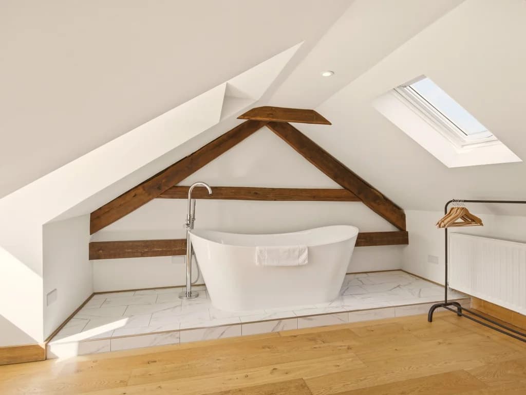 Freestanding bath beneath skylight and original exposed timber beams