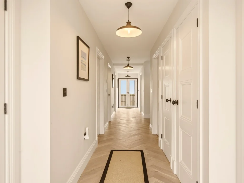 Bright ground floor hallway with herringbone flooring and bedroom access