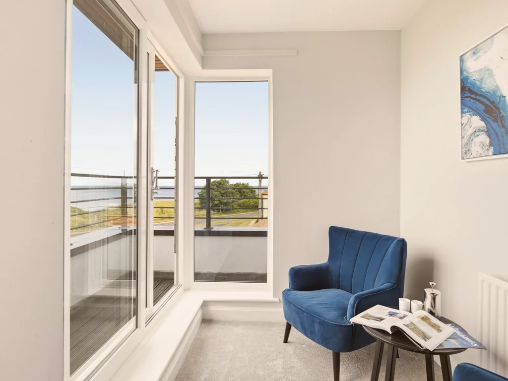 Cosy reading corner with balcony access and relaxing views towards the coastline