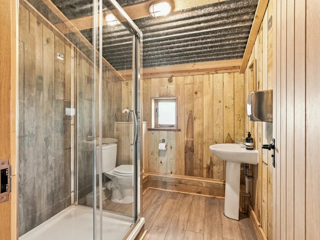 Shower room with enclosed cubicle, pedestal basin and timber walls