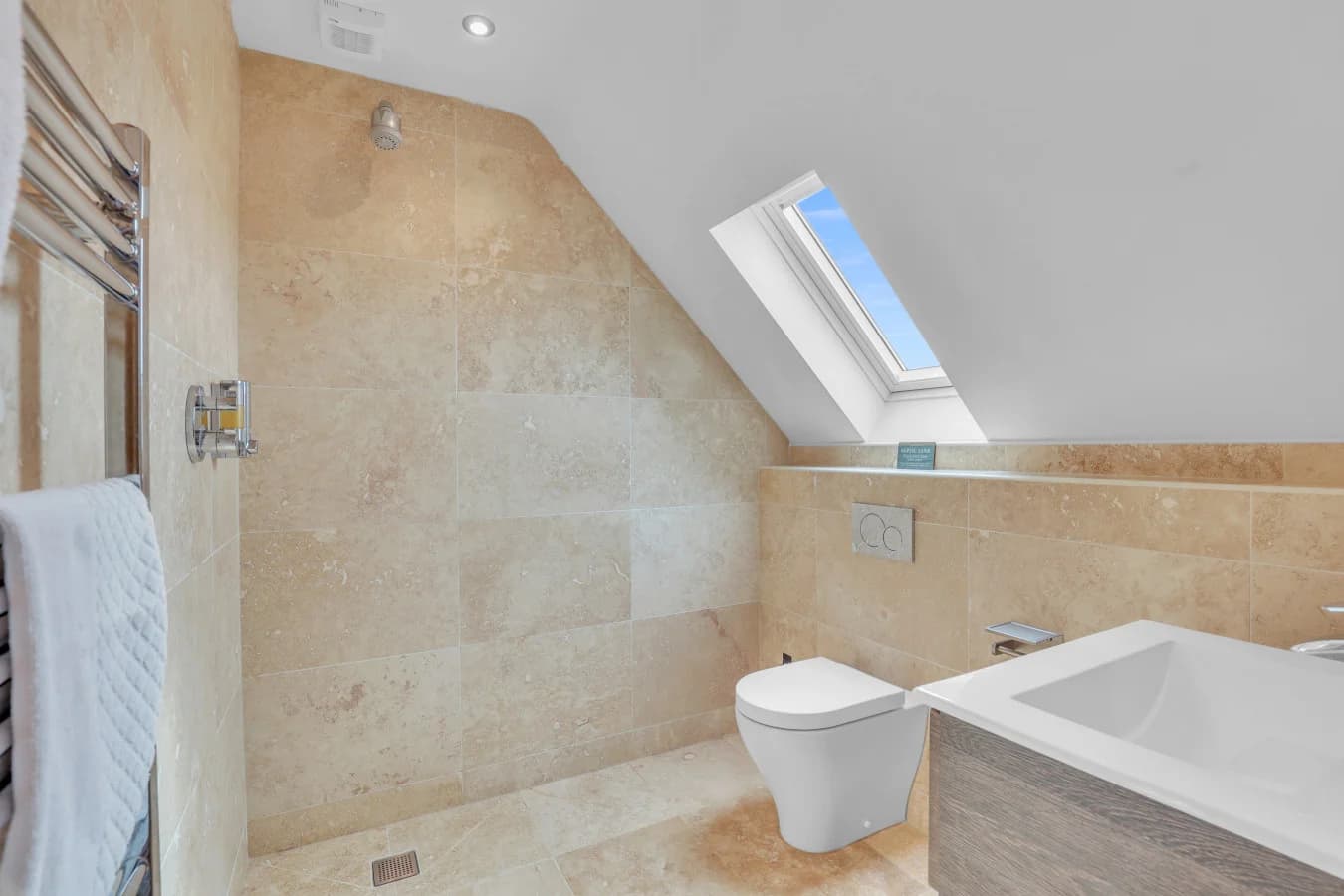 Modern ensuite bathroom with bath and skylight