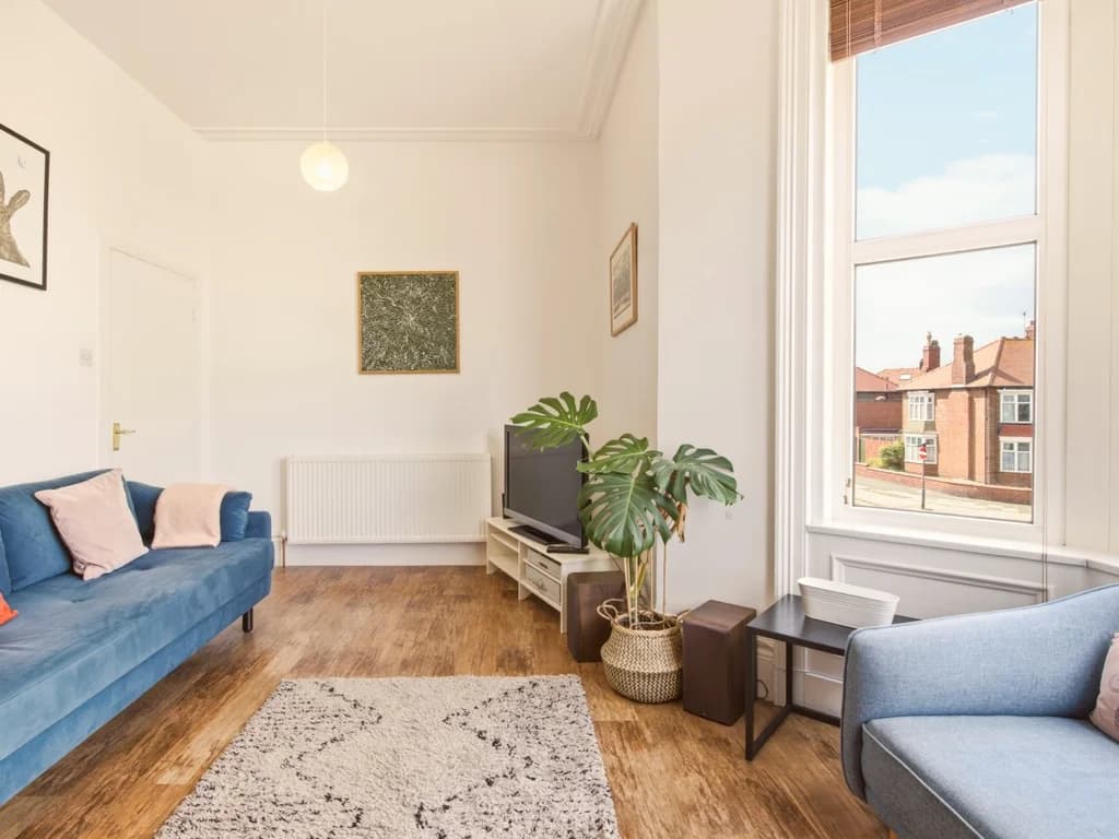 Bright living area with bay window, sofa seating and TV.