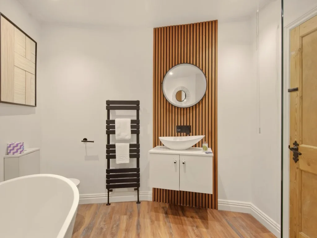Family bathroom with freestanding bath, wood slat feature wall and basin.