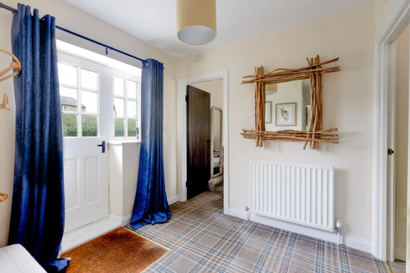 Entrance hall with tartan flooring, navy drapes and rustic mirror