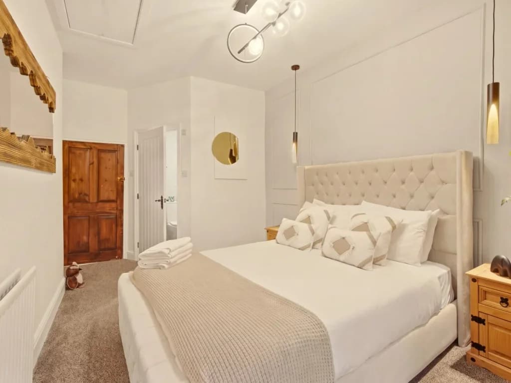 Second-floor king bedroom with tufted headboard and warm neutral decor.