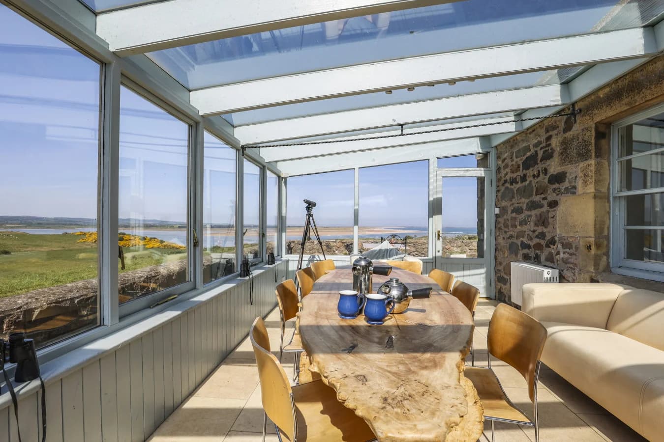 Conservatory with dining table, seating, and Budle Bay views