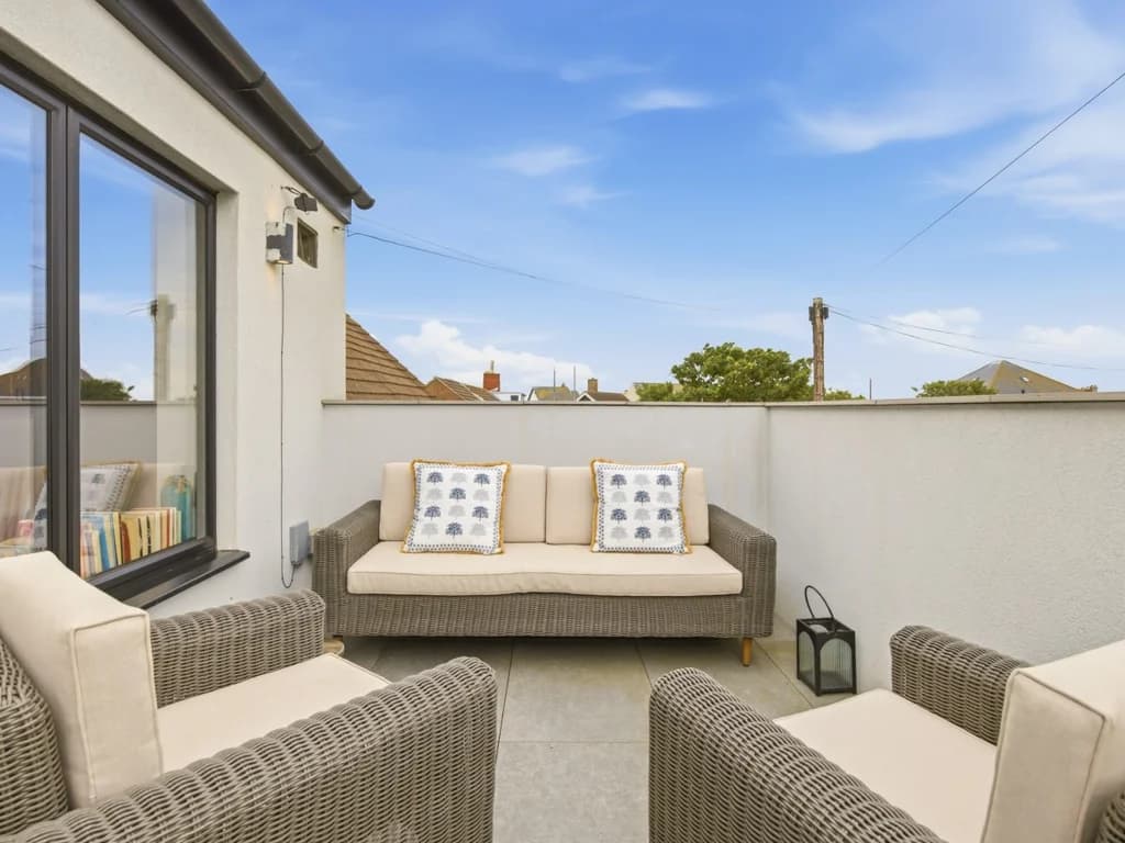 Private balcony with woven lounge seating and cushioned outdoor sofa