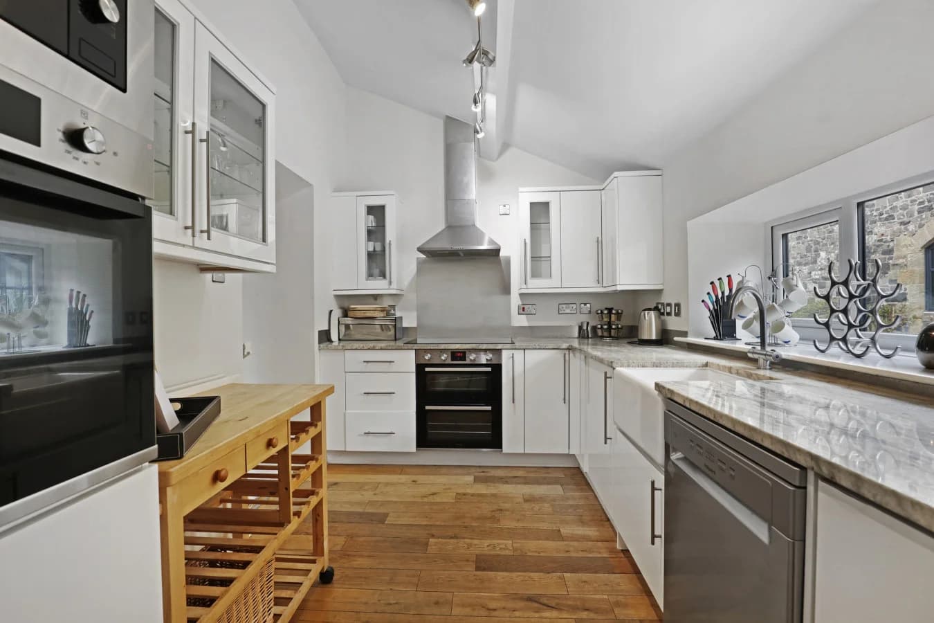 White kitchen with marble-effect worktops and oak flooring