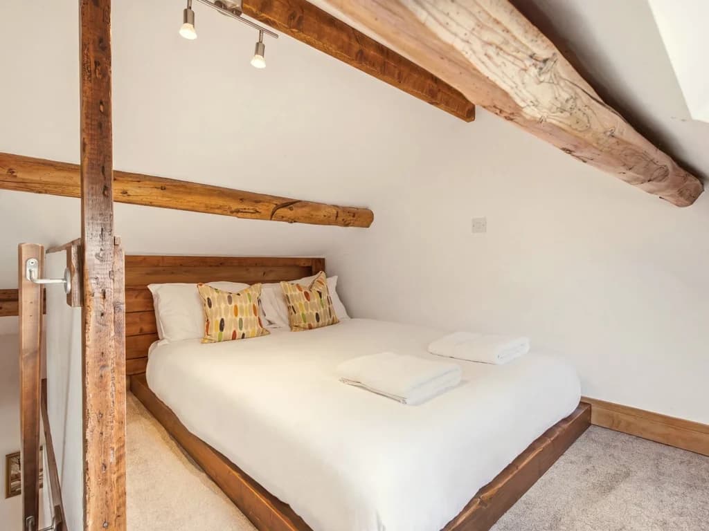 Queen-size Hayloft bed tucked beneath original exposed wooden beams