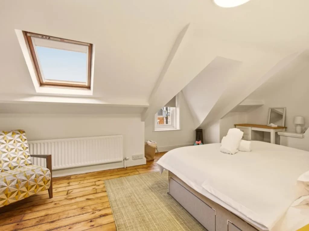 Super king-size bedroom with skylight, wooden flooring and lounge chair