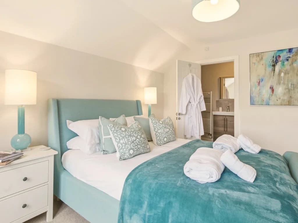 First floor king bedroom with en-suite access and soft aqua furnishings