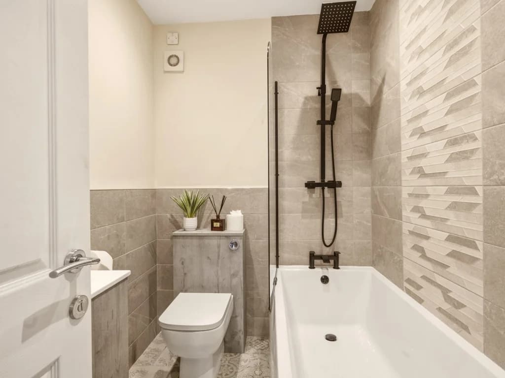 Family bathroom with bath, overhead shower and textured feature tiles.
