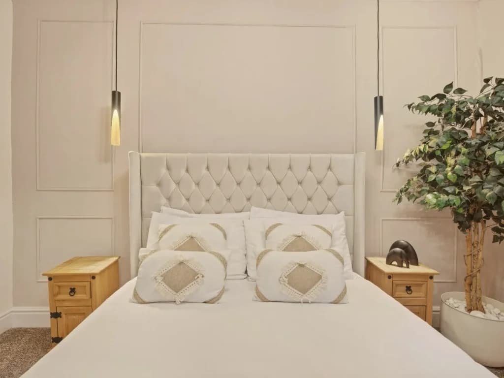 Close view of the king bed with pendant lights and panelled backdrop.