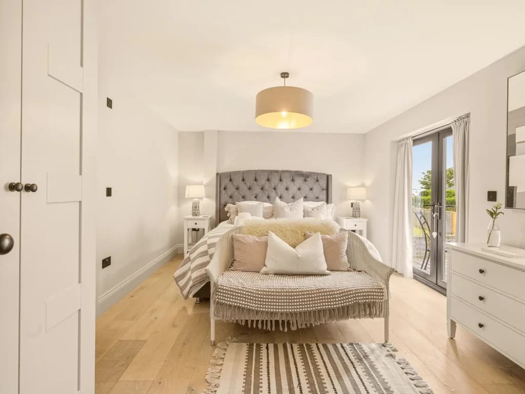 Bright super king bedroom with balcony access and elegant upholstered headboard