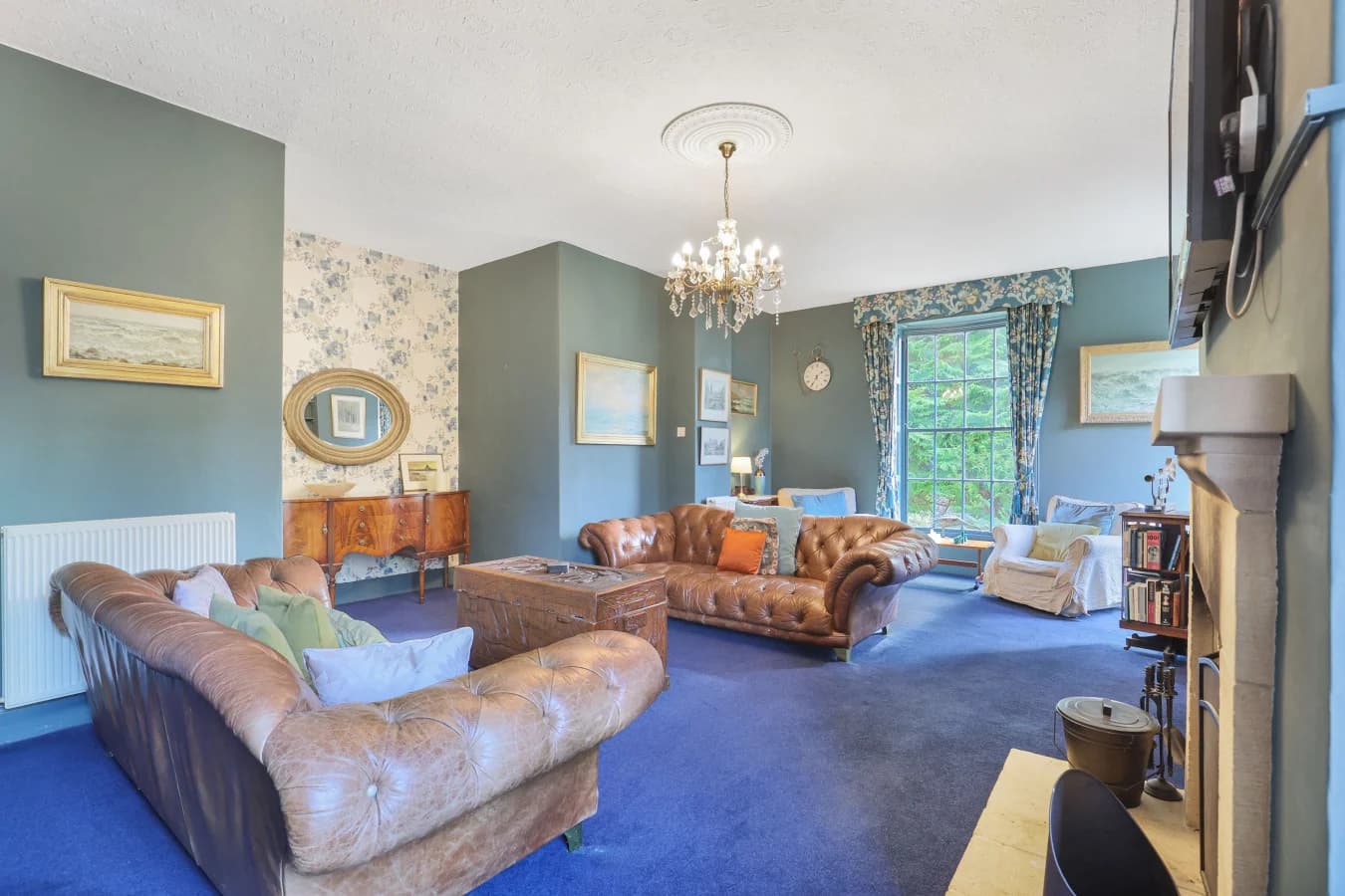 Elegant sitting room with leather sofas, open fire and garden views