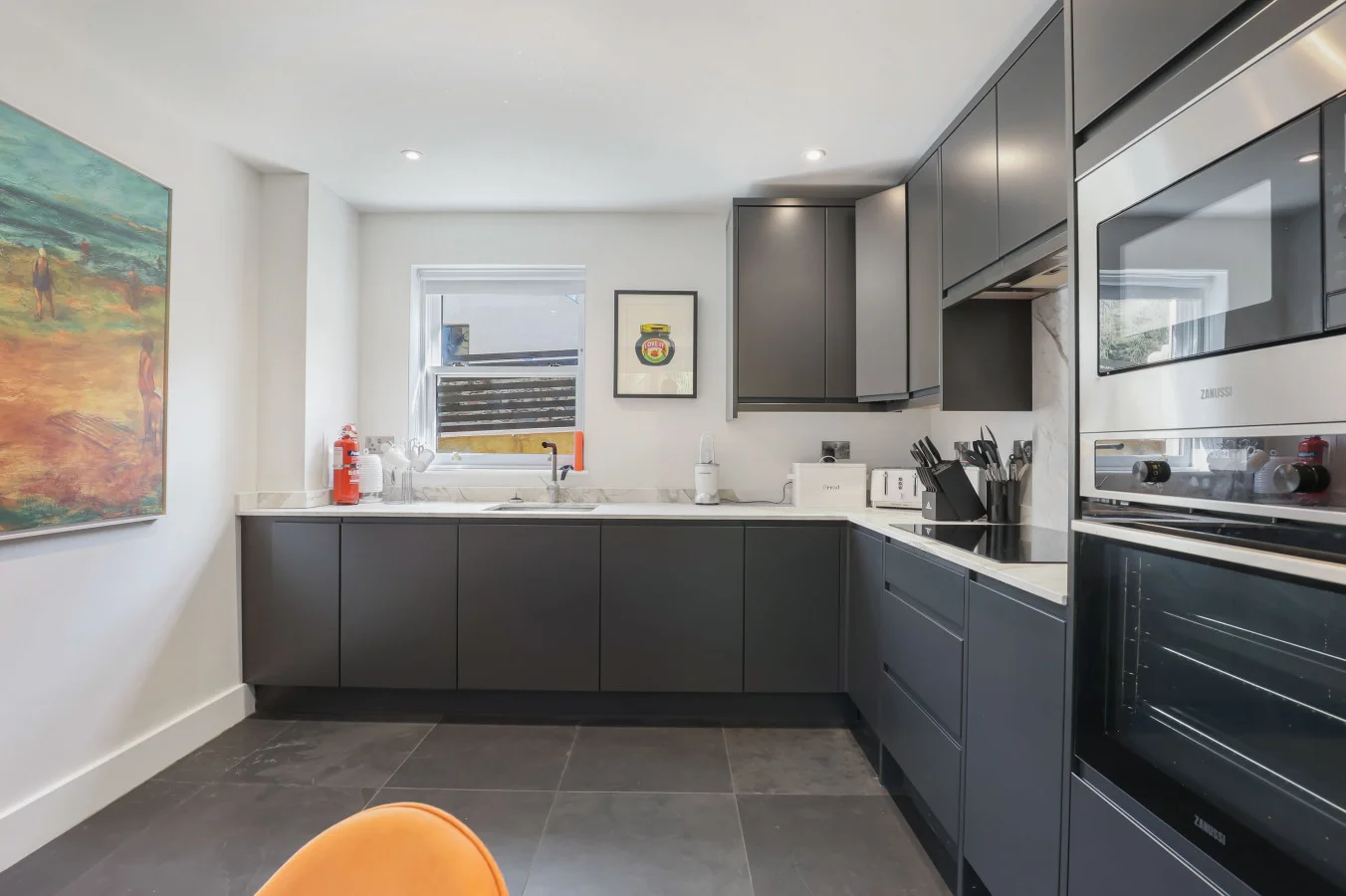 Contemporary kitchen with charcoal cabinetry and integrated appliances