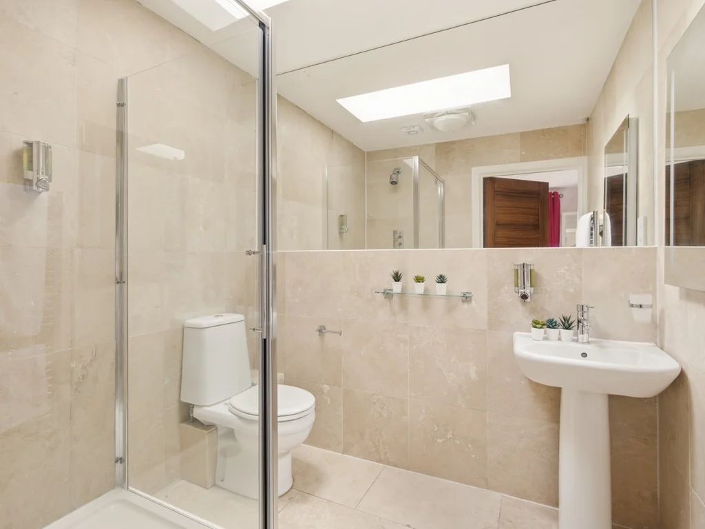 Walk-in shower room with beige tiles and timber door finishes.