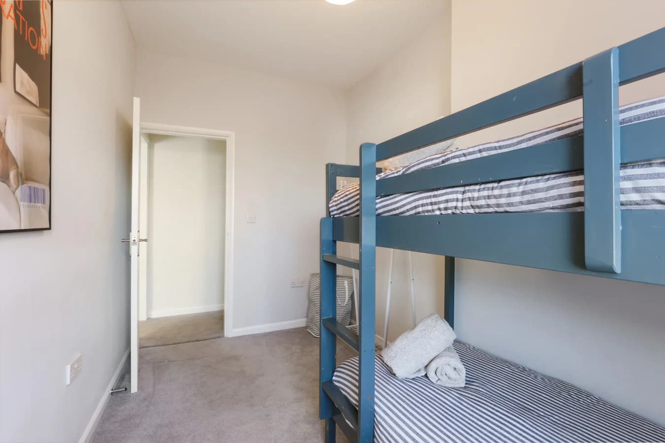 Twin bunk room with striped bedding and a bright, minimalist design
