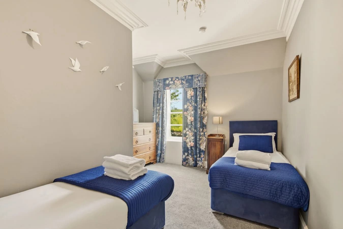 Twin bedroom with blue upholstered beds and decorative wall details