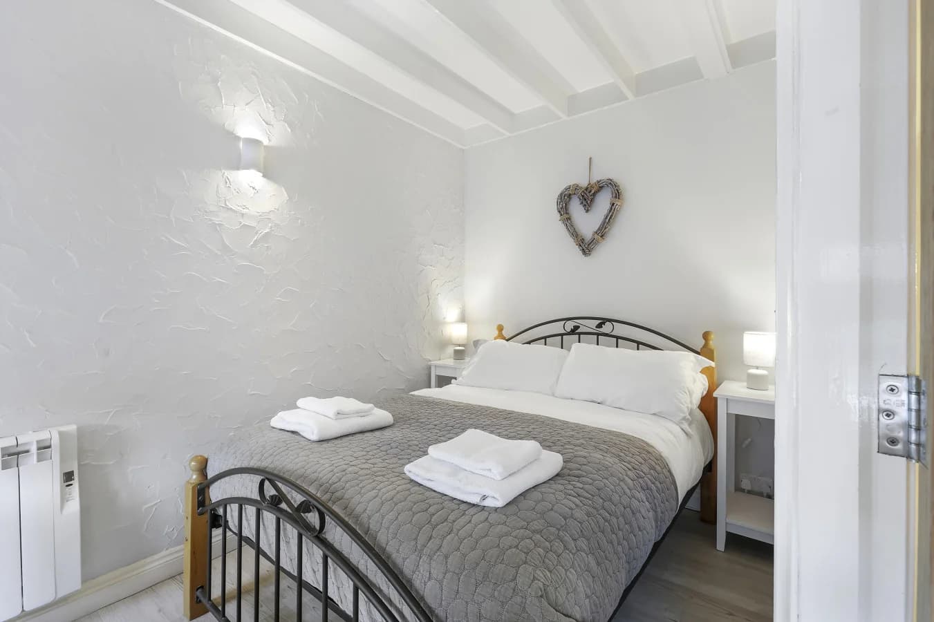 Double bedroom with wrought-iron bed and soft coastal-inspired tones